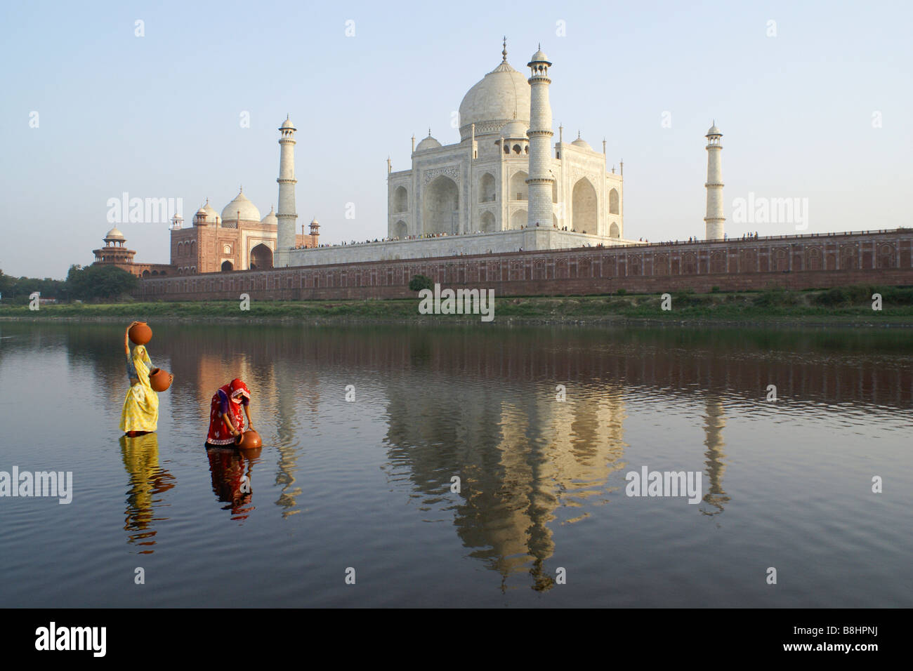 Les femmes obtenir de l'eau à partir de la rivière Yamuna avec Taj Mahal en arrière-plan, Agra, Inde Banque D'Images