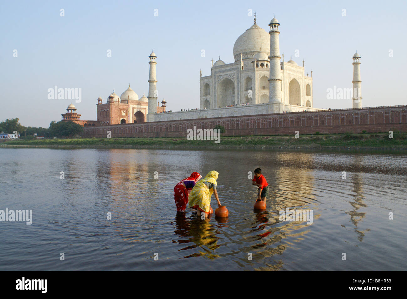 Les femmes et l'eau de boy getting rivière Yamuna avec Taj Mahal en arrière-plan, Agra, Inde Banque D'Images