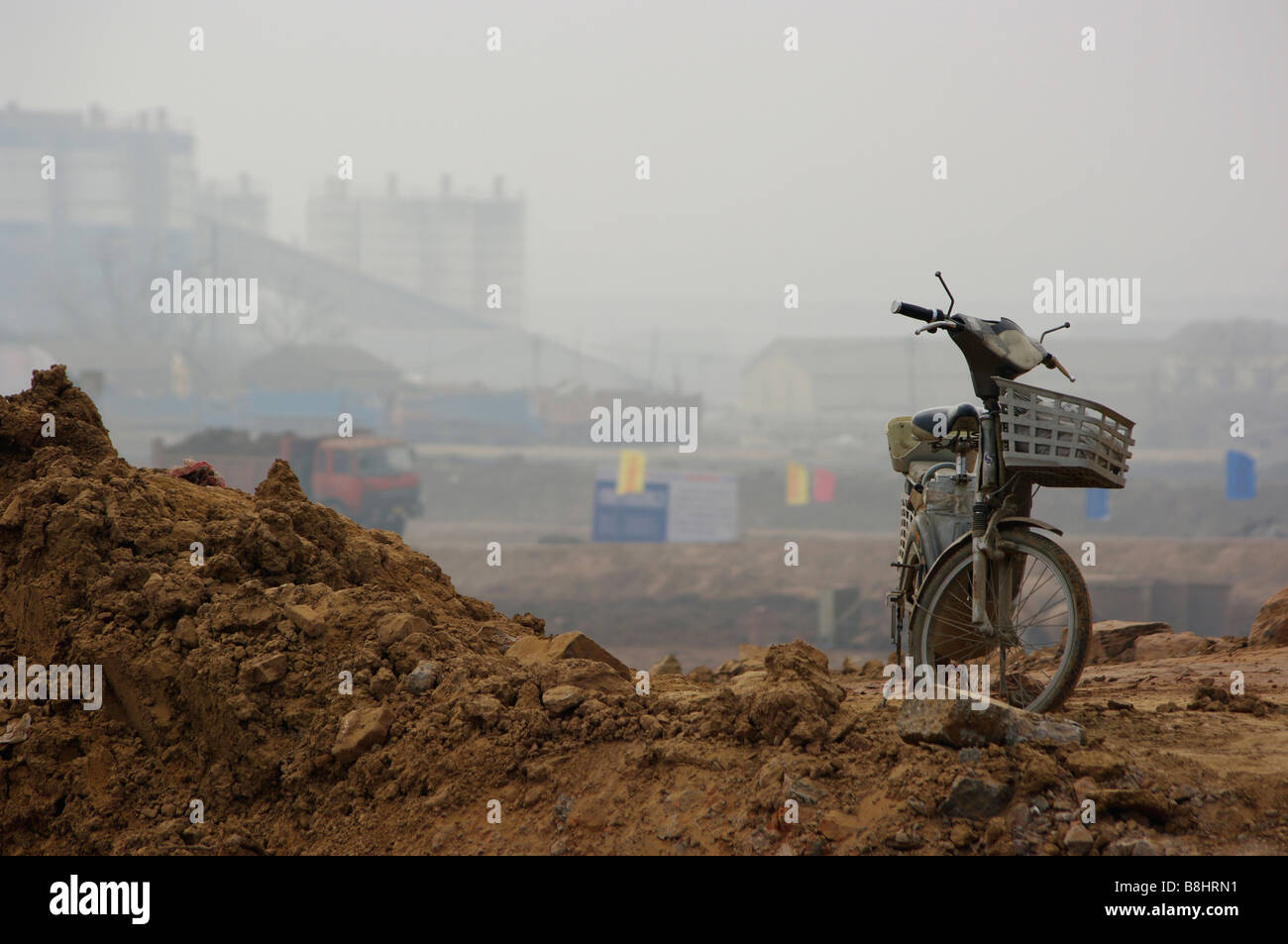 Un vieux cyclomoteur est assise sur un tas de terre à l'occasion d'un grand chantier de construction de Chine en attente de travailleurs de continuer l'édifice. Banque D'Images