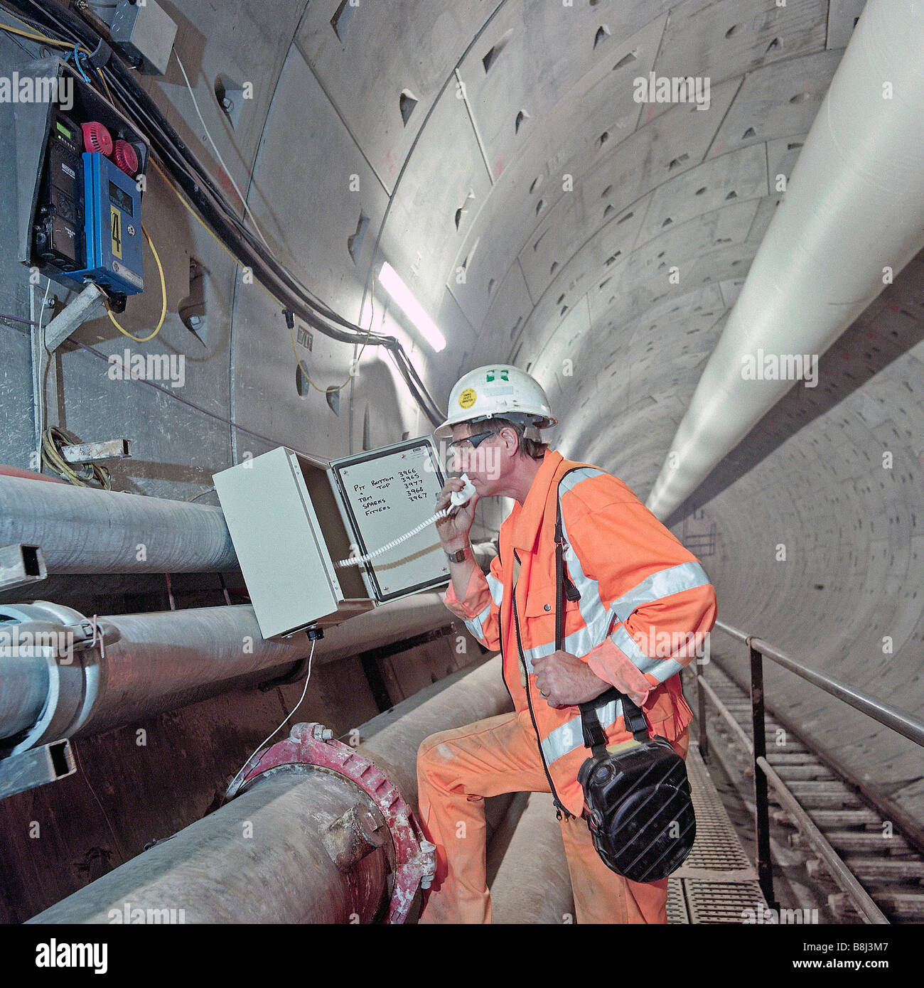 Bureau de sécurité portant un auto-sauveteur vérifie le système de téléphone d'urgence dans le Thames Tunnel sur le Channel Tunnel Rail Link Banque D'Images