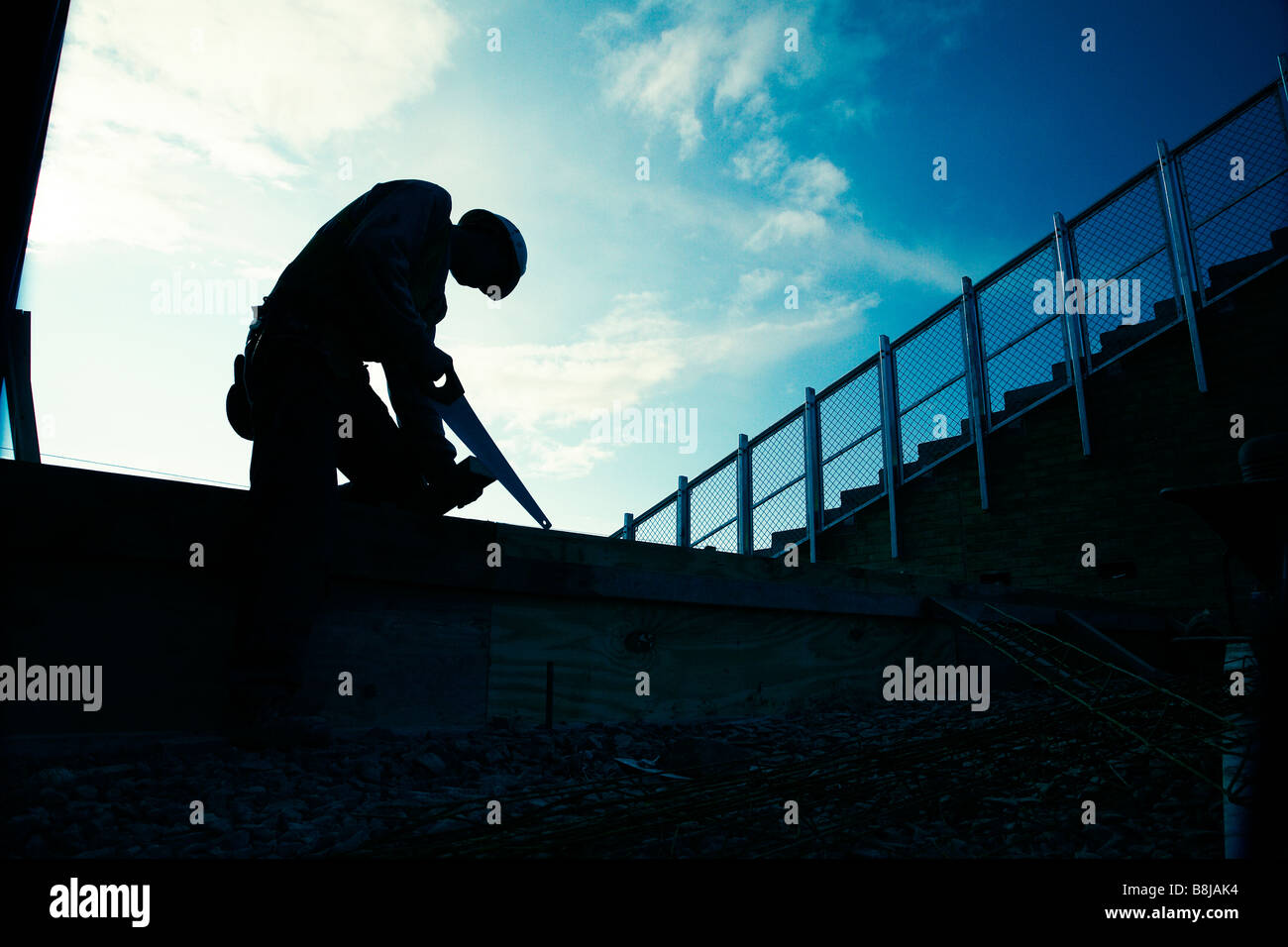 Silhouette d'un ouvrier à l'aide d'une scie Banque D'Images