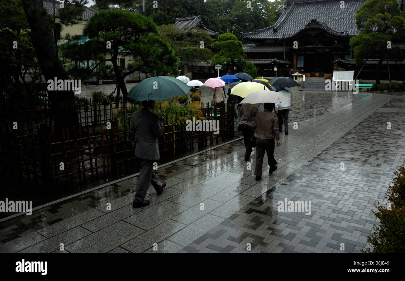 Les pèlerins arrivant à Tokyo's Sengaku-ji avec parasols colorés dans la pluie Banque D'Images