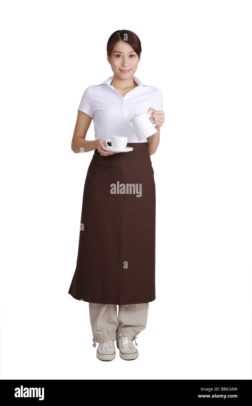 Young waitress holding une théière et une tasse à la recherche à l'appareil photo Banque D'Images