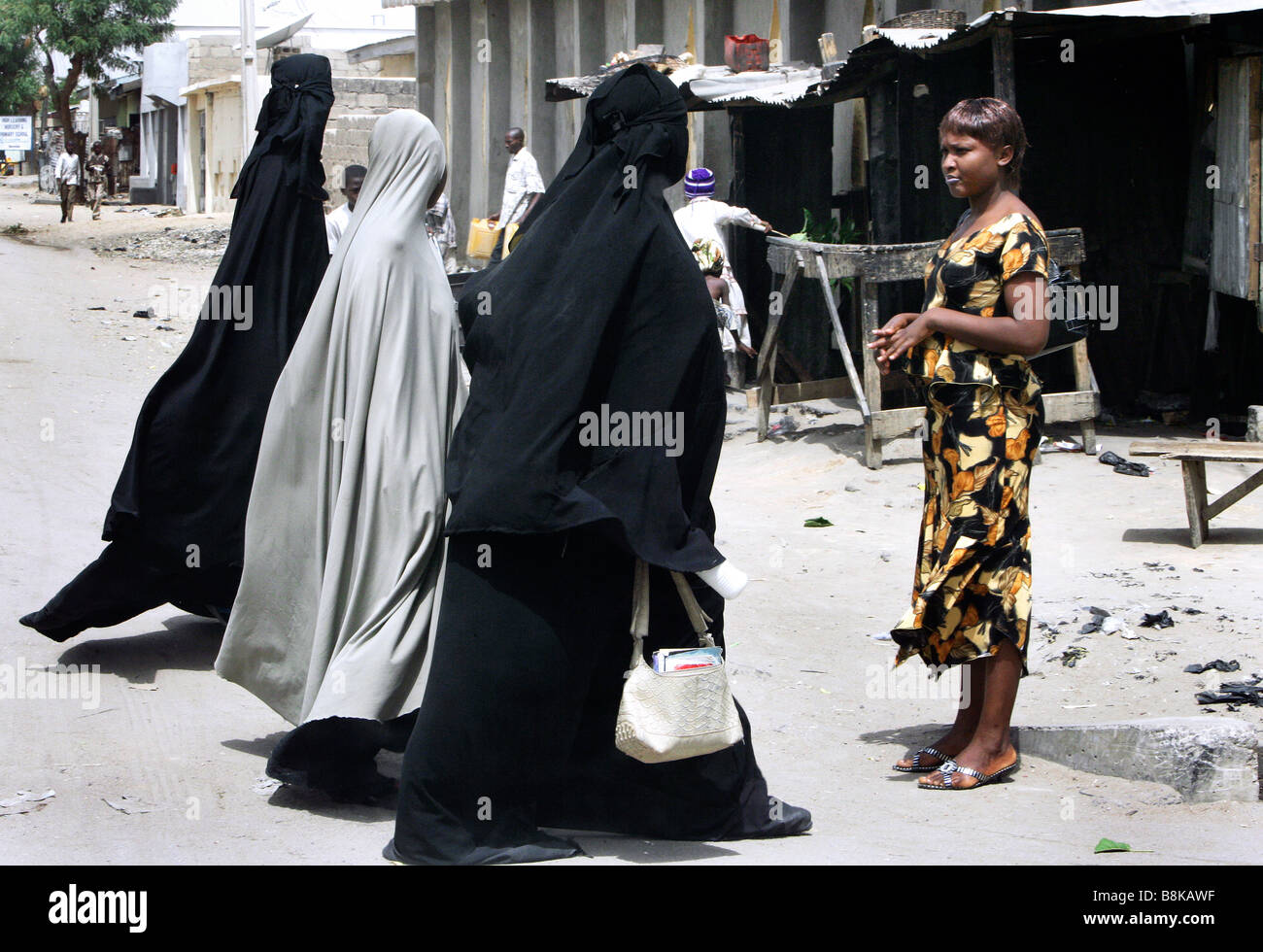 Un sceptique à la femme chrétienne moderne habillé en regardant les femmes musulmanes portant un corps plein de Burka. Maiduguri, l'État de Borno, Nigeria Banque D'Images