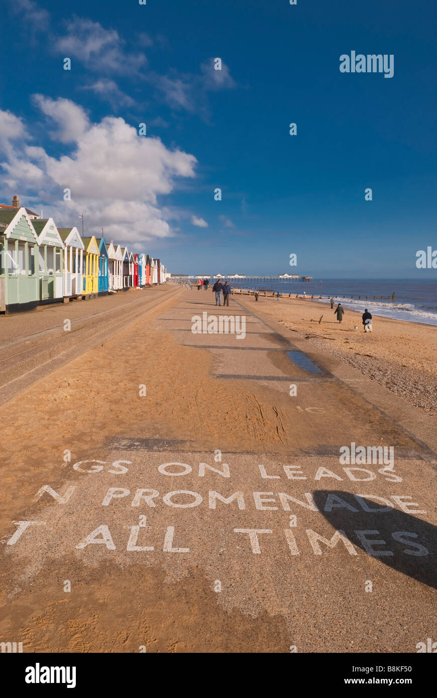 Les gens qui marchent le long de la promenade de la plage de Southwold sur une belle journée avec les chiens sur avis mène à l'avant-plan Banque D'Images