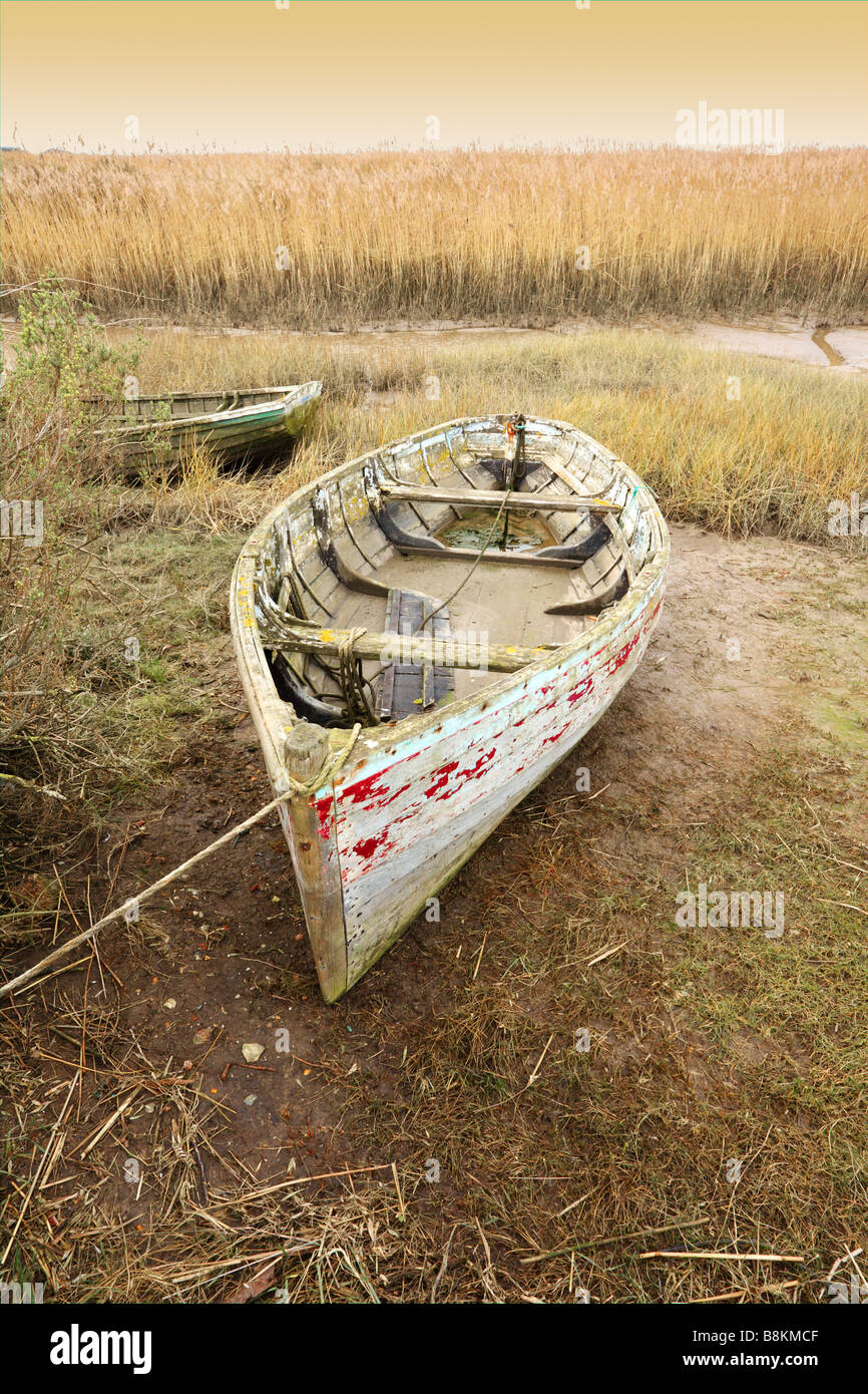 Vieux bateaux inutilisés se trouvant à marée basse, les marais salants de la côte nord du comté de Norfolk [Royaume-Uni]. Banque D'Images