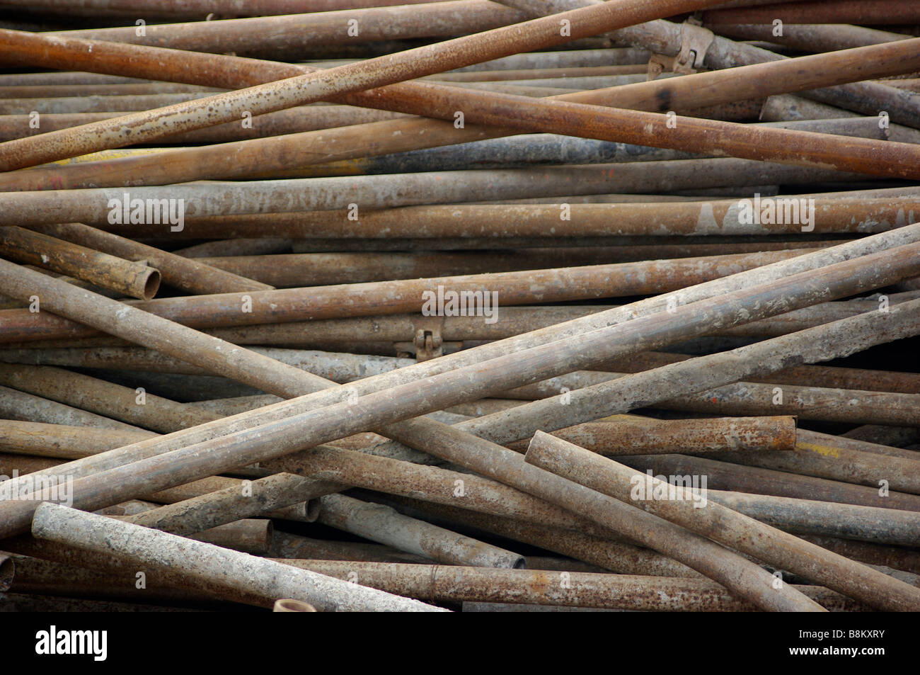 Acier, fer, aluminium barres de métal et les tuyaux sont empilés sur un chantier où le béton et le ciment sont verser dans des capacités. Banque D'Images