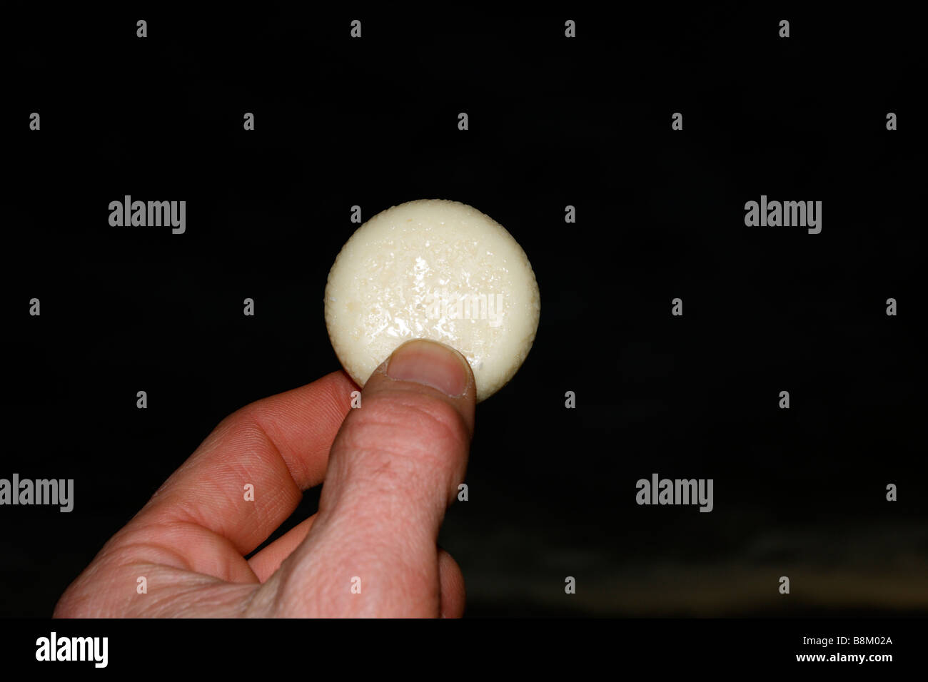 Roue de fromage dans les doigts. Sur noir Banque D'Images