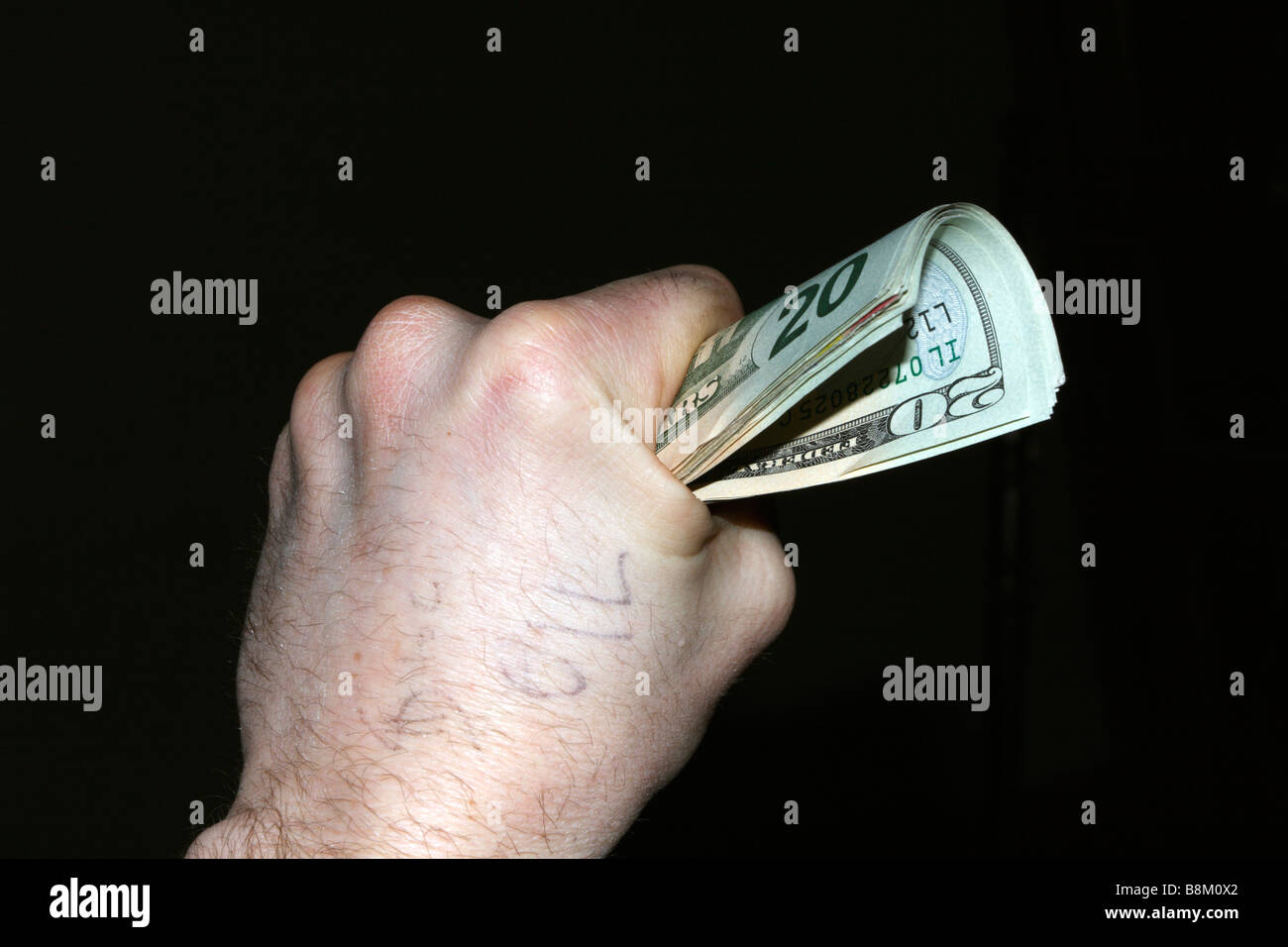Caucasian Male main gauche serrant tas de USA vingt piastres avec le mot "oil" écrit sur la main. Banque D'Images