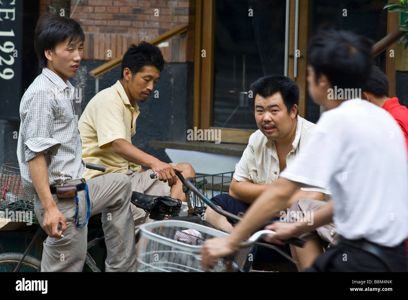 Les livreurs à vélo Shanghai discutent dans la rue• Banque D'Images