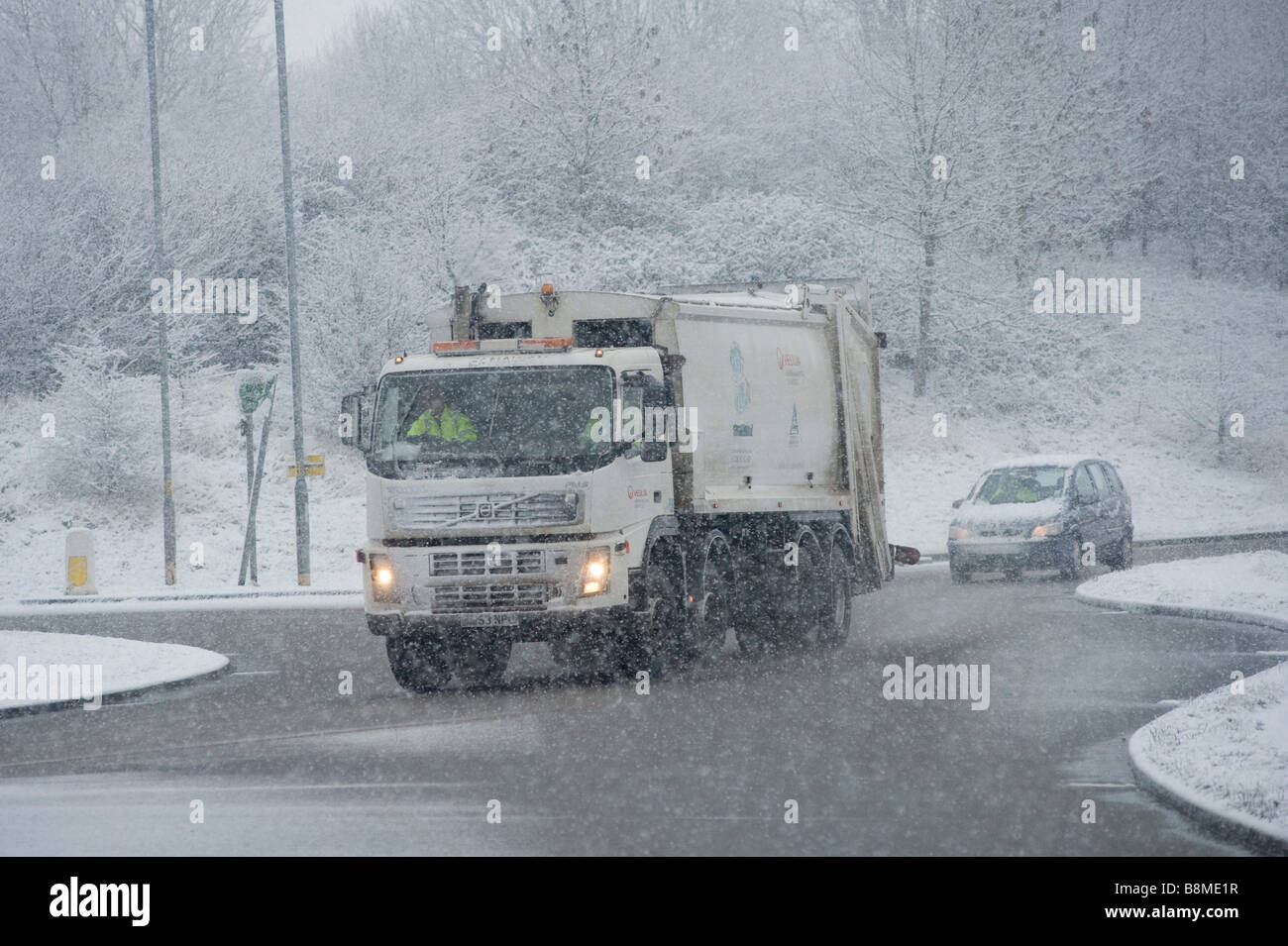 En Angleterre, un camion-camion de déchets conduit lentement sur une route enneigée en hiver. Banque D'Images