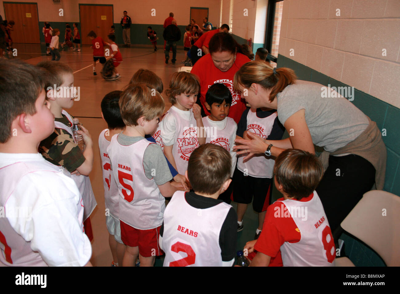 Coach indique à l'équipe de basket-ball des jeunes au cours d'un jeu (9-12 ans) United States, groupe d'enfants dans un gymnase public Banque D'Images