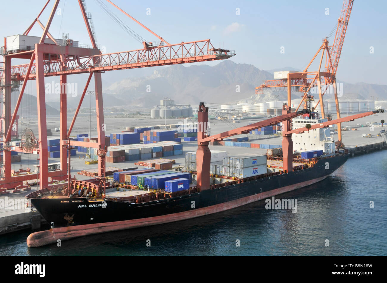 Boxship au port de Fujairah sur le golfe d'Oman conteneurs empilés sur le quai et conteneur navire à côté avec arc bulbeux Banque D'Images