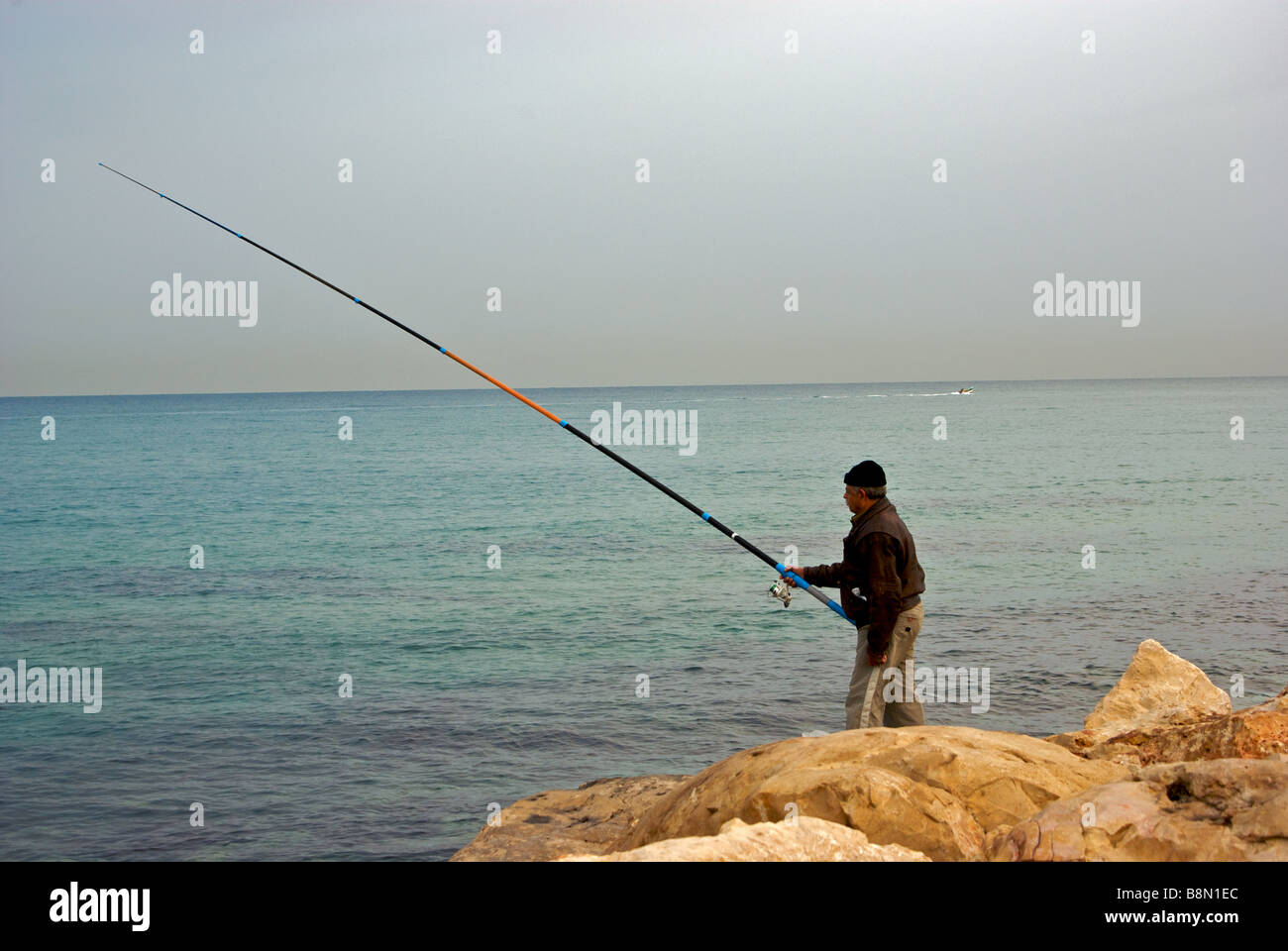 Pêche pêcheur solitaire Mer Méditerranée à partir de la digue promenade longue tige de brise-lames avec surf et spinning reel Banque D'Images