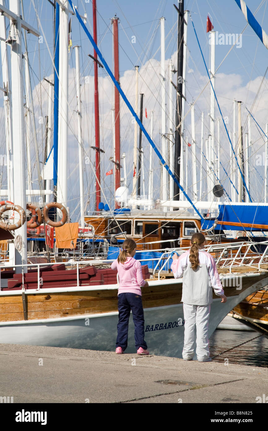 Deux enfants de la capture de poissons en face de yachts amarrés dans un port méditerranéen à Fethiye Turquie Banque D'Images