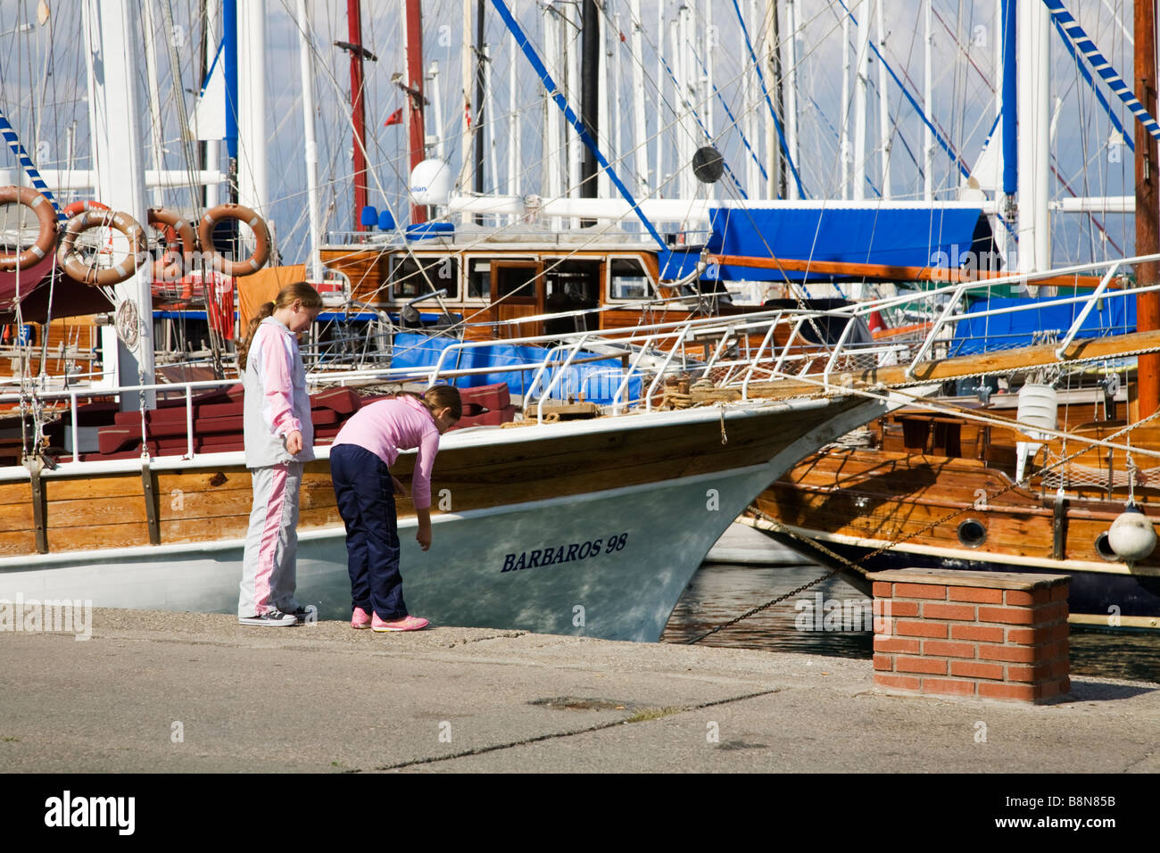 Deux enfants en face de pêche bateaux amarrés dans un port méditerranéen à Fethiye Turquie Banque D'Images