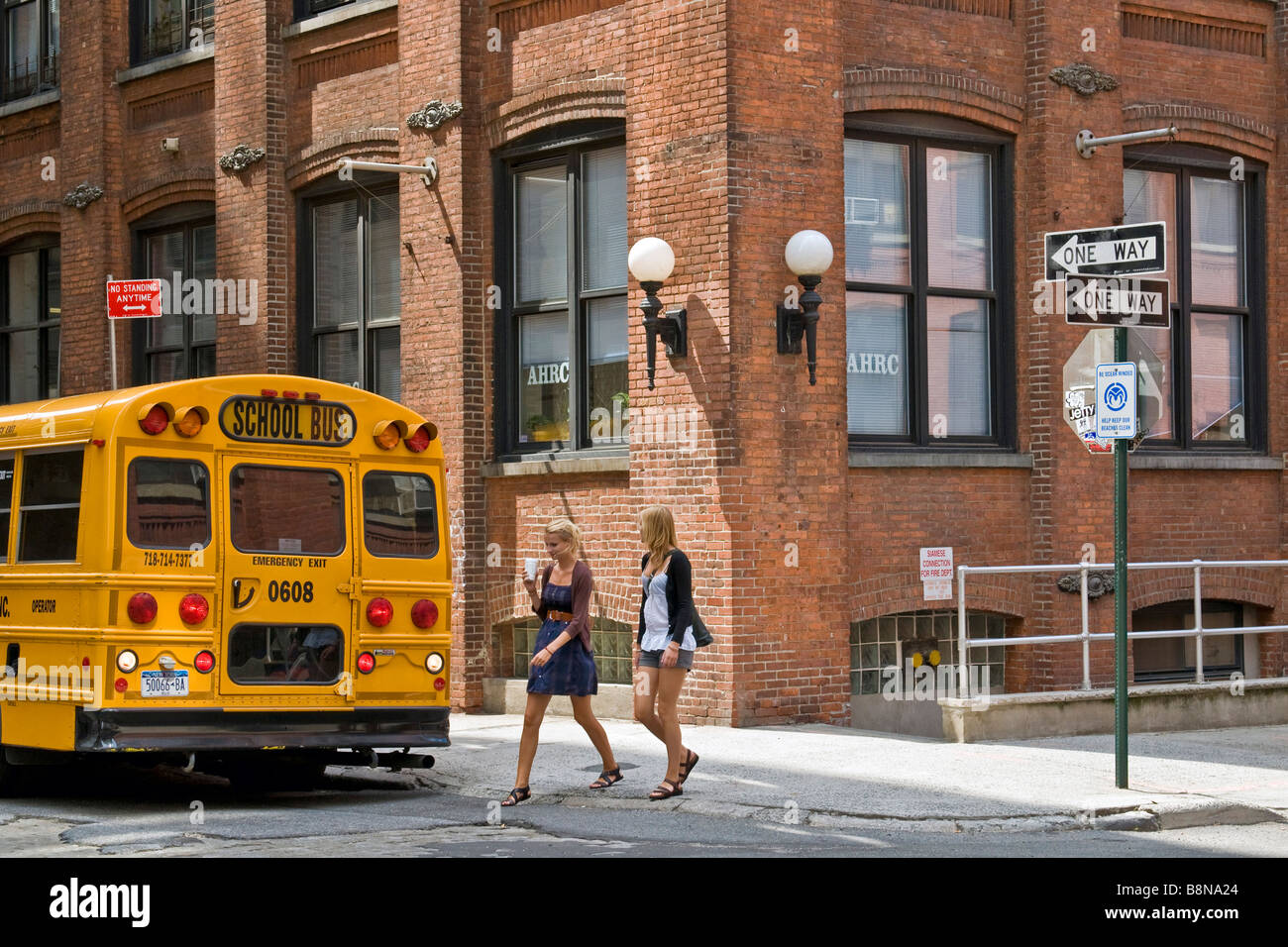Deux jeunes femmes qui traversent la route à proximité d'un arrêt de bus scolaire, Brooklyn Banque D'Images