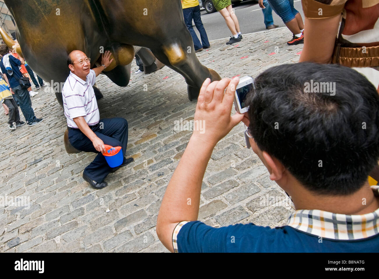 Les touristes photographiant la charge de bronze de taureau dans le centre-ville de New York City Banque D'Images