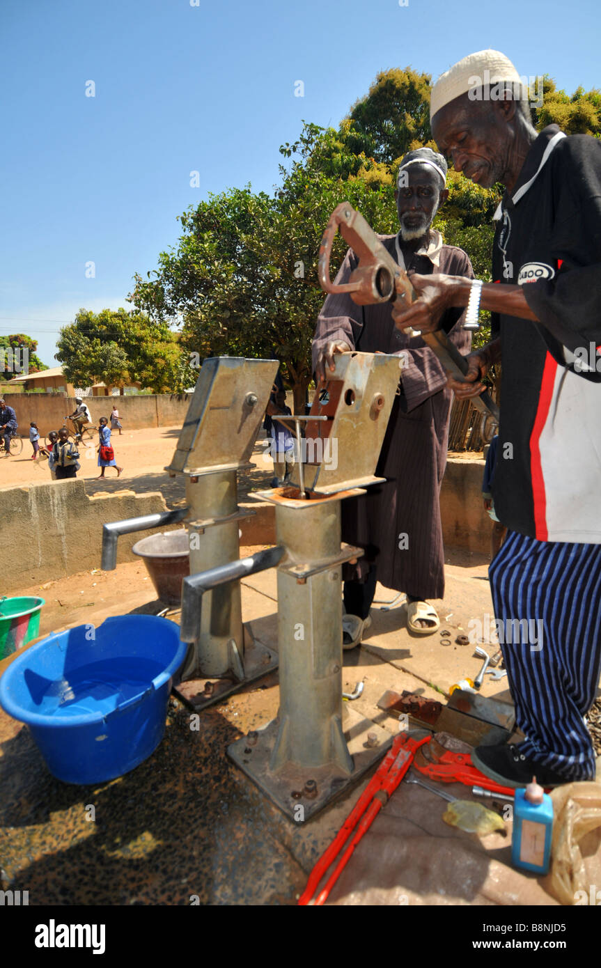 Les hommes de réparer une pompe à eau dans un village de la Gambie, Afrique de l'Ouest Banque D'Images