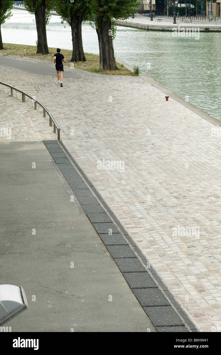 France, Paris, Canal Saint-Martin, personne du jogging le long du bord de l'eau Banque D'Images