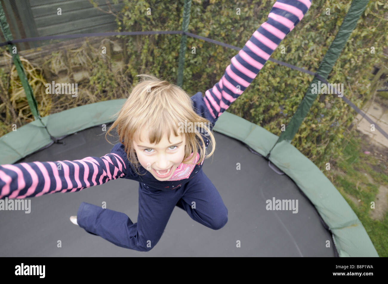 Une fillette de six ans de rebondir sur un trampoline Banque D'Images