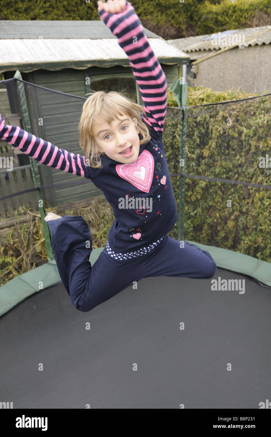 Une fillette de six ans de rebondir sur un trampoline Banque D'Images