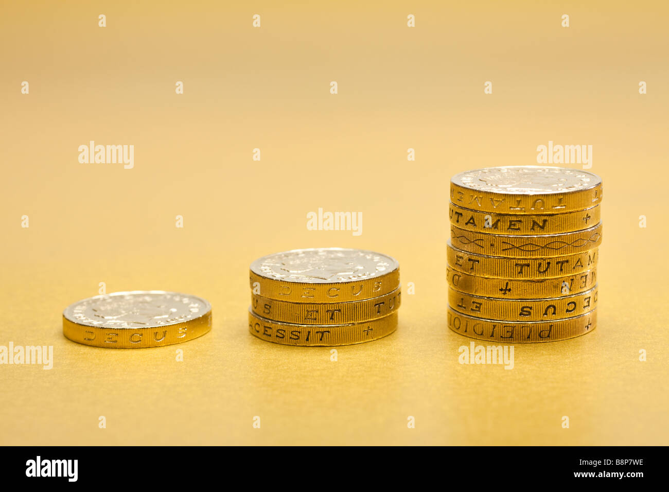 Payer. Des piles croissantes de pièces d'une livre sterling de £1 sur fond doré, économiser Banque D'Images
