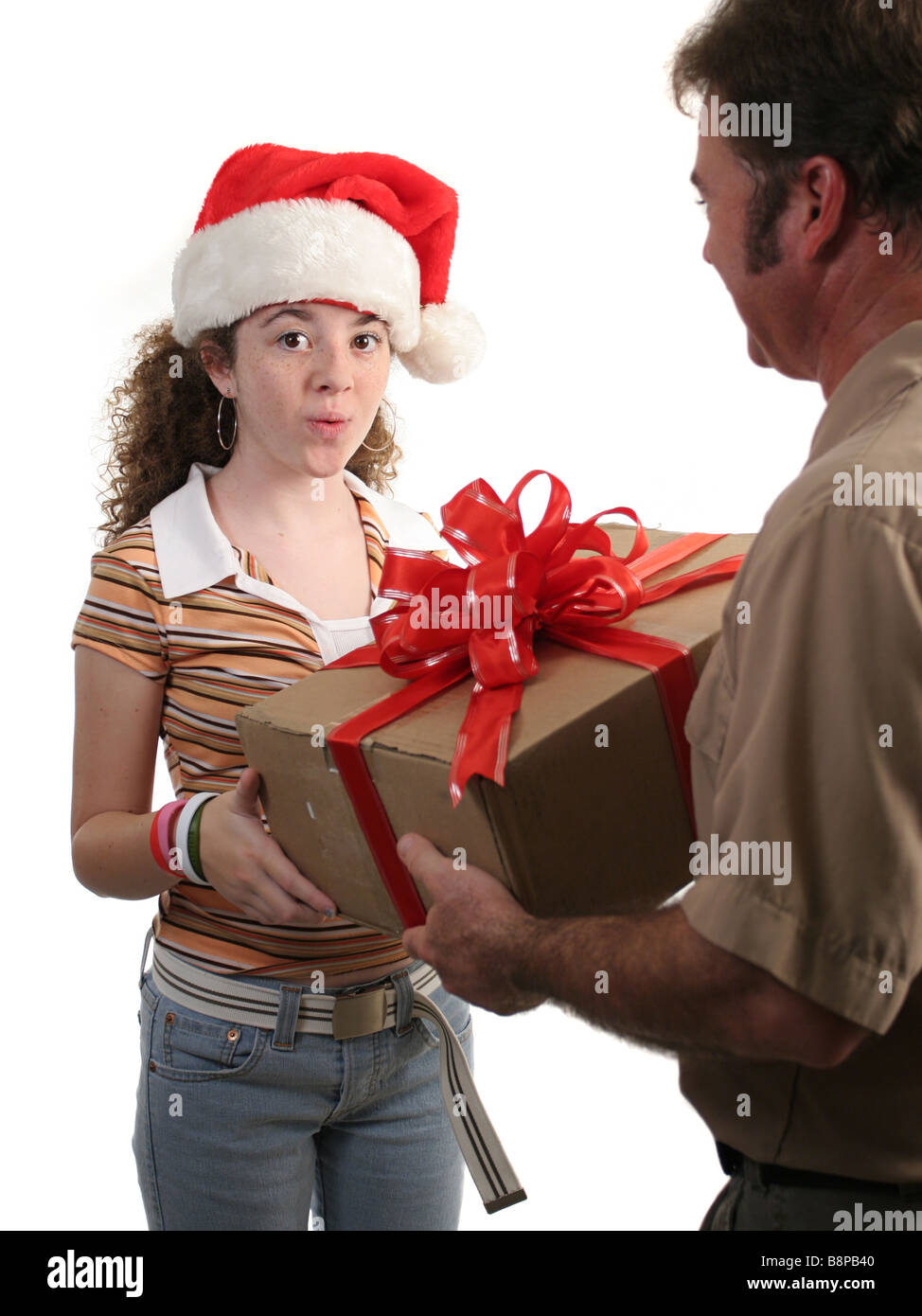 Une surprise girl in a santa hat recevoir un cadeau de Noël d'un homme isolé de livraison Banque D'Images