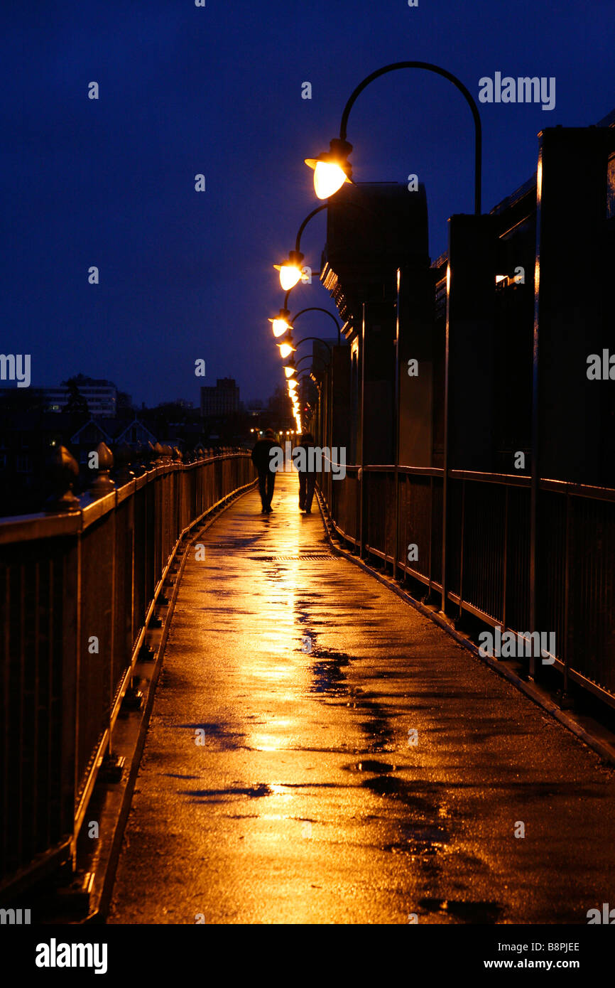 Les piétons marchant sur un pont ferroviaire Fulham humide, Fulham, London Banque D'Images