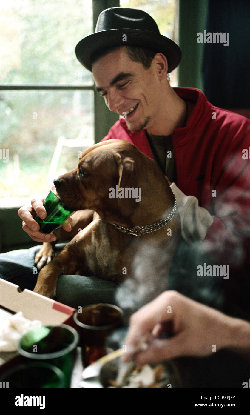 Jeune homme de laisser le chien boire dans le verre Banque D'Images