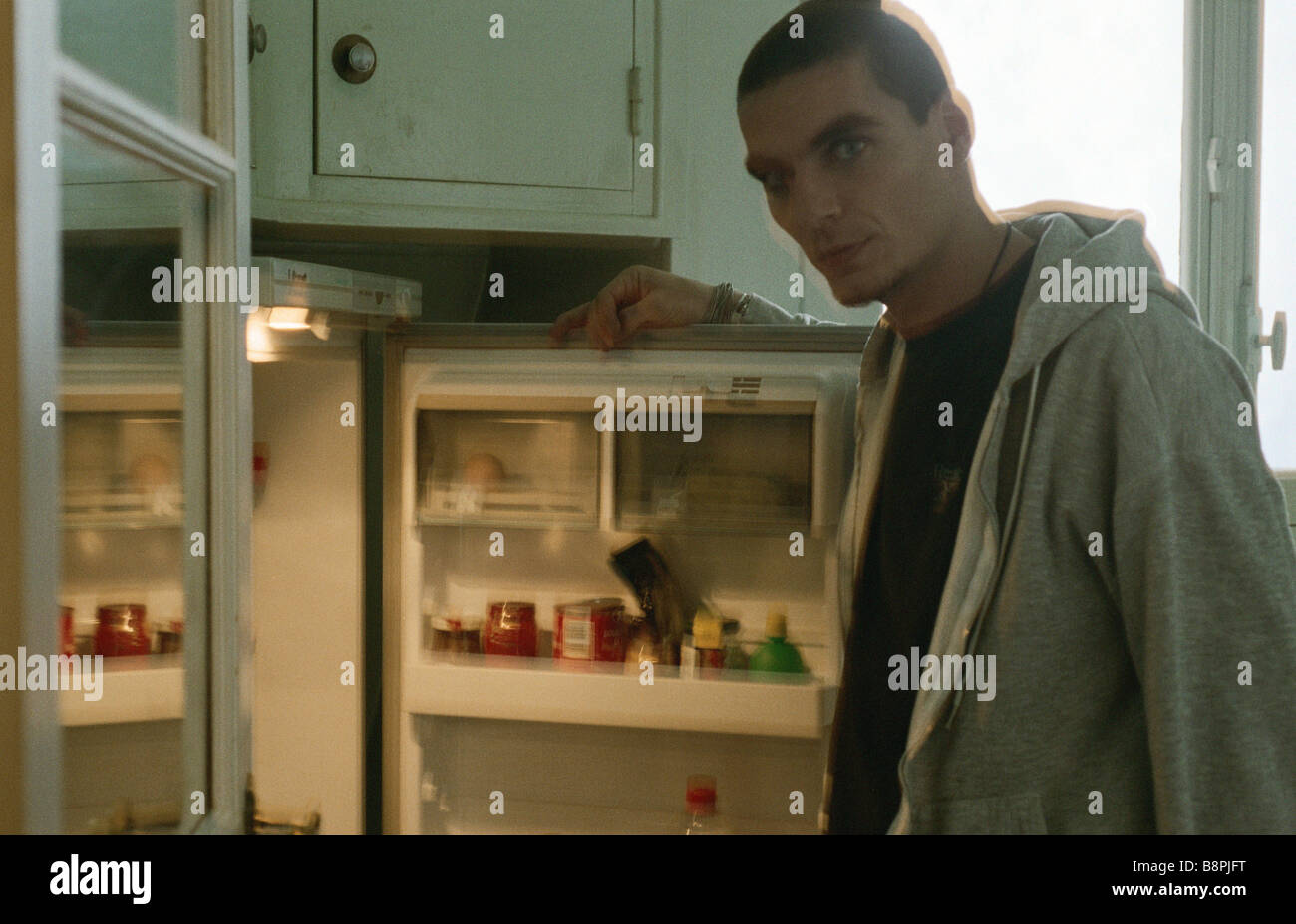 Jeune homme debout devant ouvrir réfrigérateur, looking at camera Banque D'Images