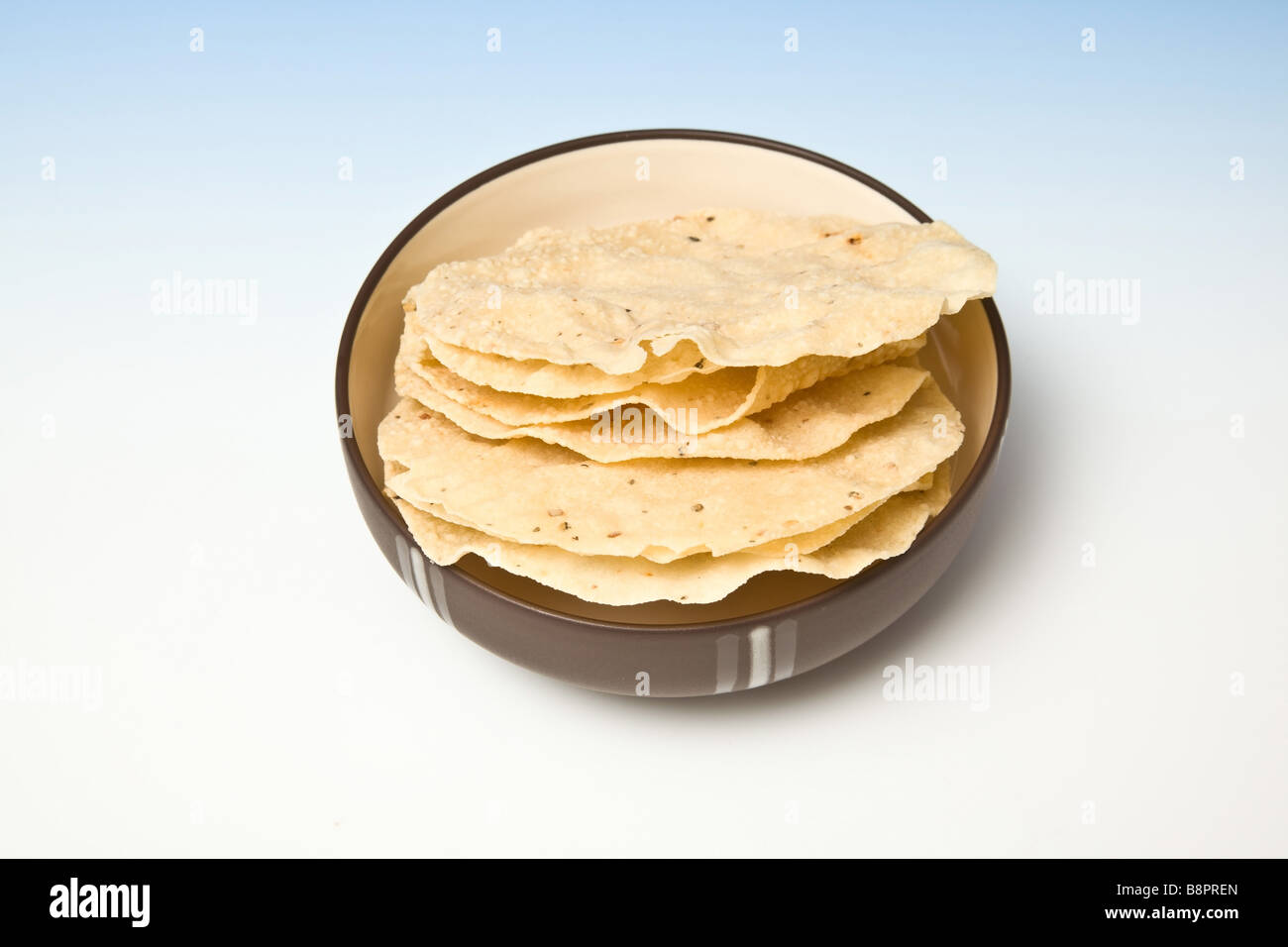 Bol de Poppadoms sur un fond bleu dégradé studio Banque D'Images