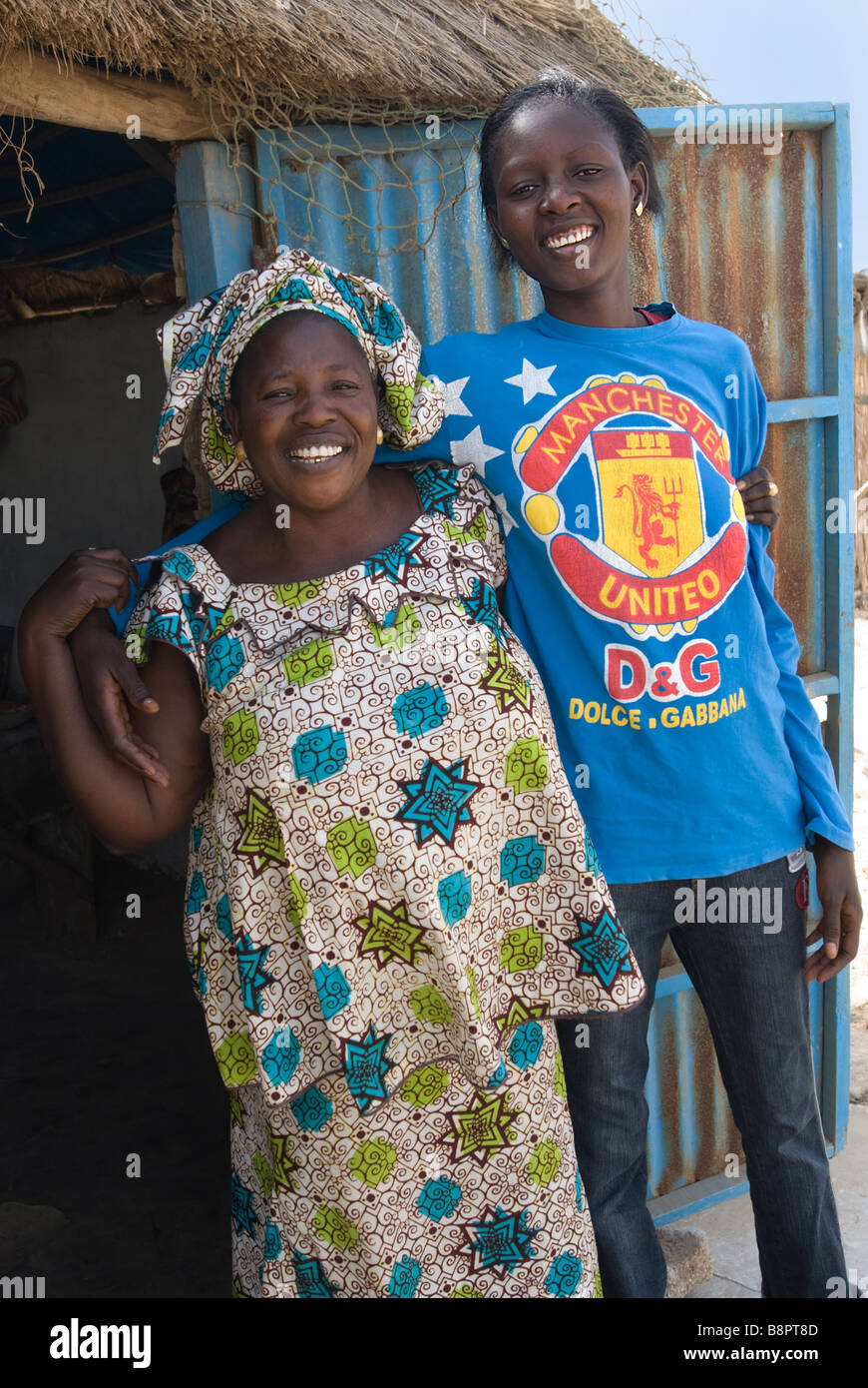 Mère sénégalaise en vêtements traditionnels avec teenage daughter wearing Manchester United Football Shirt Banque D'Images