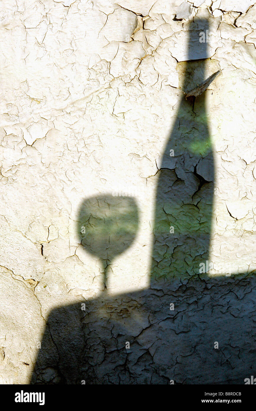 Photographie artistique de l'ombre d'une bouteille de vin vert et verre de vin exprimés contre mur texturé Still Life Copy Space Banque D'Images