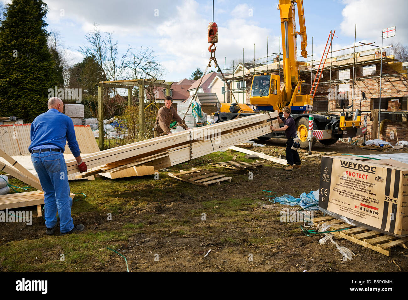 Le déchargement des ouvriers de livraison de bois de toiture un envoi prêt à construire un toit Banque D'Images