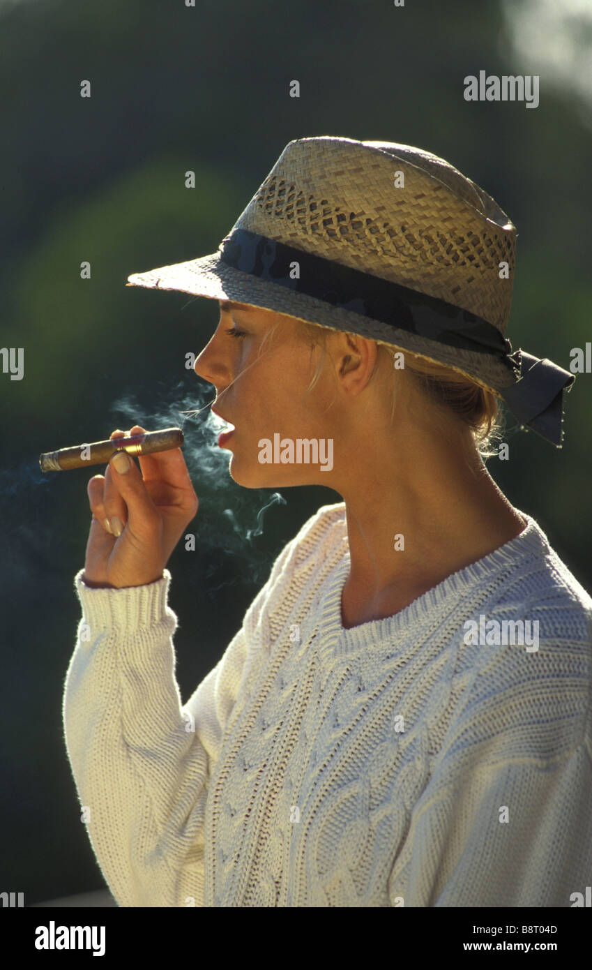 Femme portant un chapeau est fumer un cigare Banque D'Images
