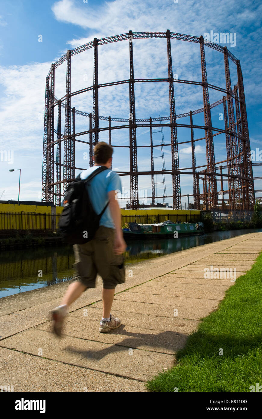 Un homme marche le long de la piste du Canal Regent dans l'Est de Londres passé une ancienne structure travaux gaz Banque D'Images