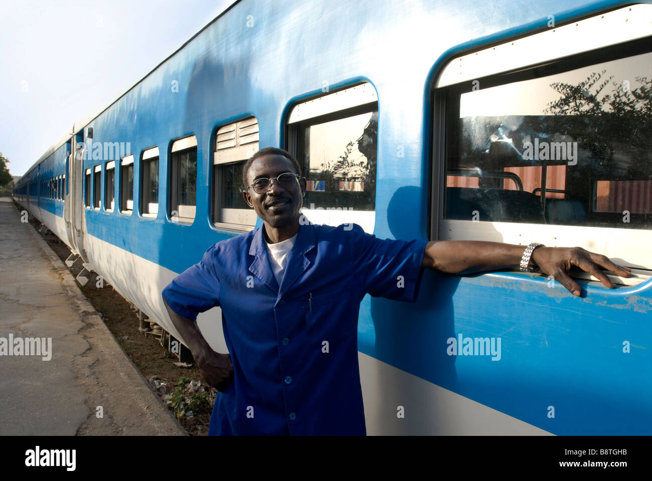Portrait d'un chef d'orchestre sénégalais devant son train bleu prêt à partir de la gare de Dakar Banque D'Images
