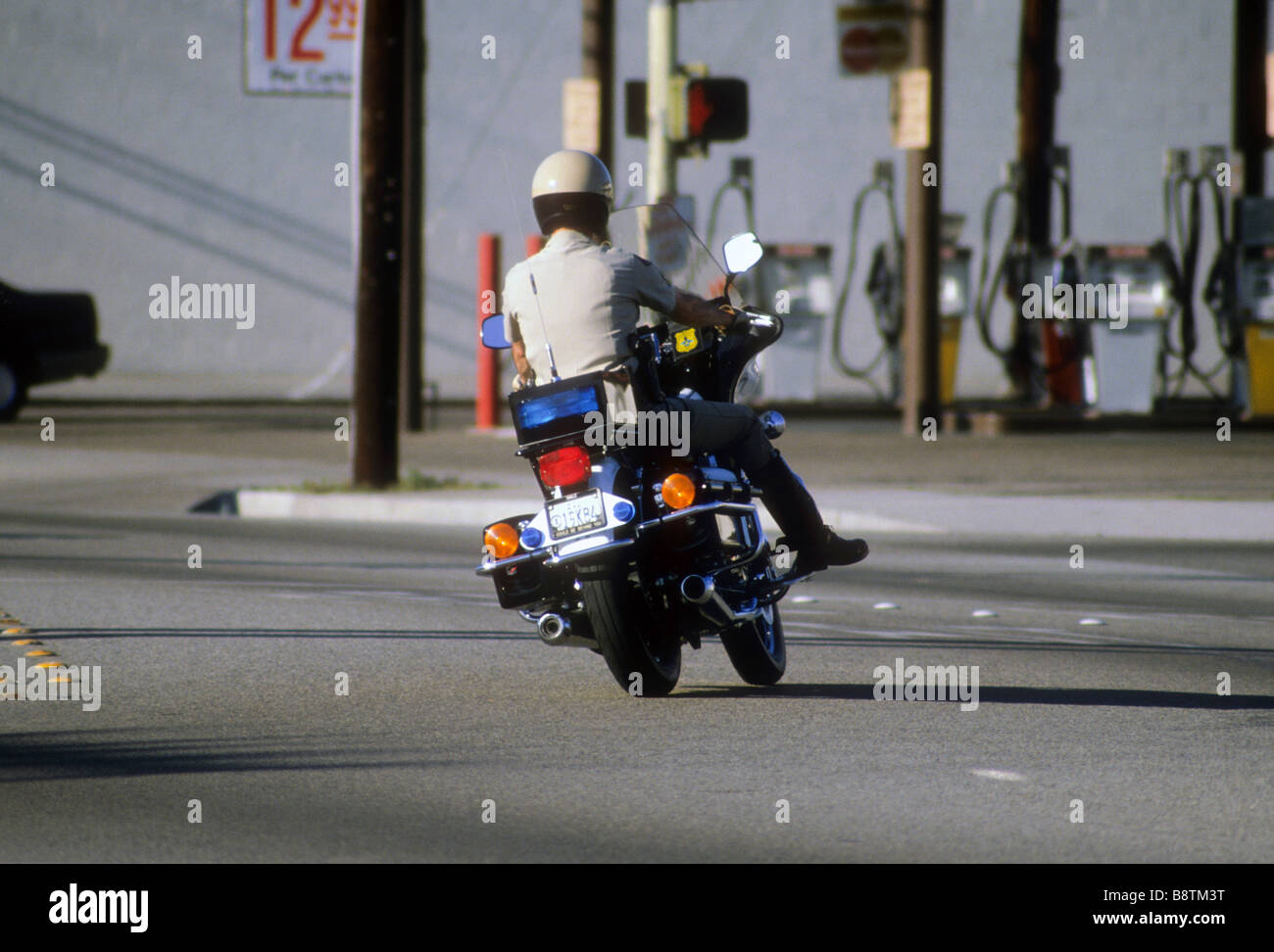 California Highway Patrol Officer sur moto cycle moteur tourne sur chaussée Banque D'Images