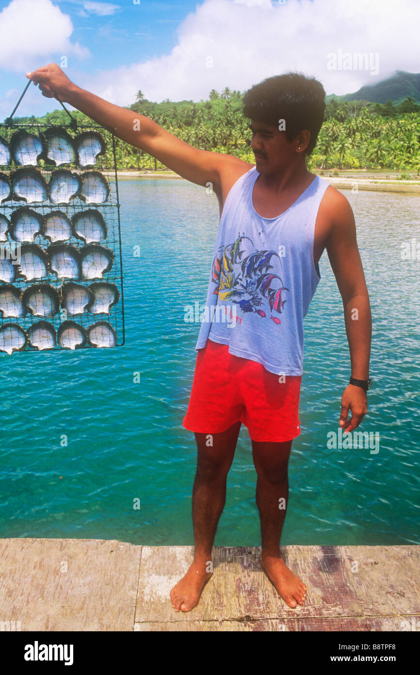 Un homme tenant la cage d'obus sur une ferme de perles noires en polynésie francaise Banque D'Images