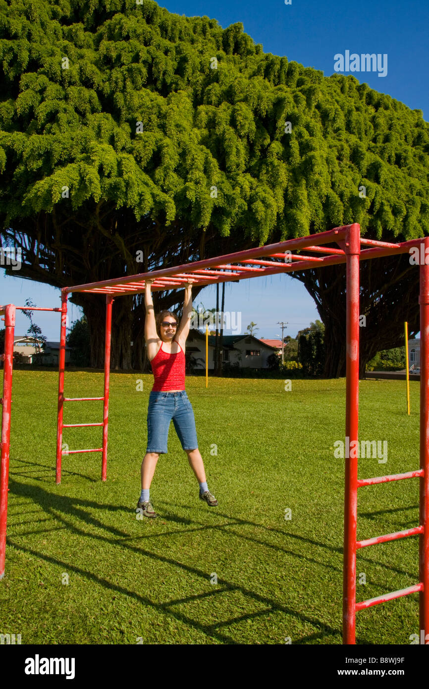 Jeune femme suspendu à une échelle horizontale dans Middleburg, Big Island, Hawaii, USA Banque D'Images