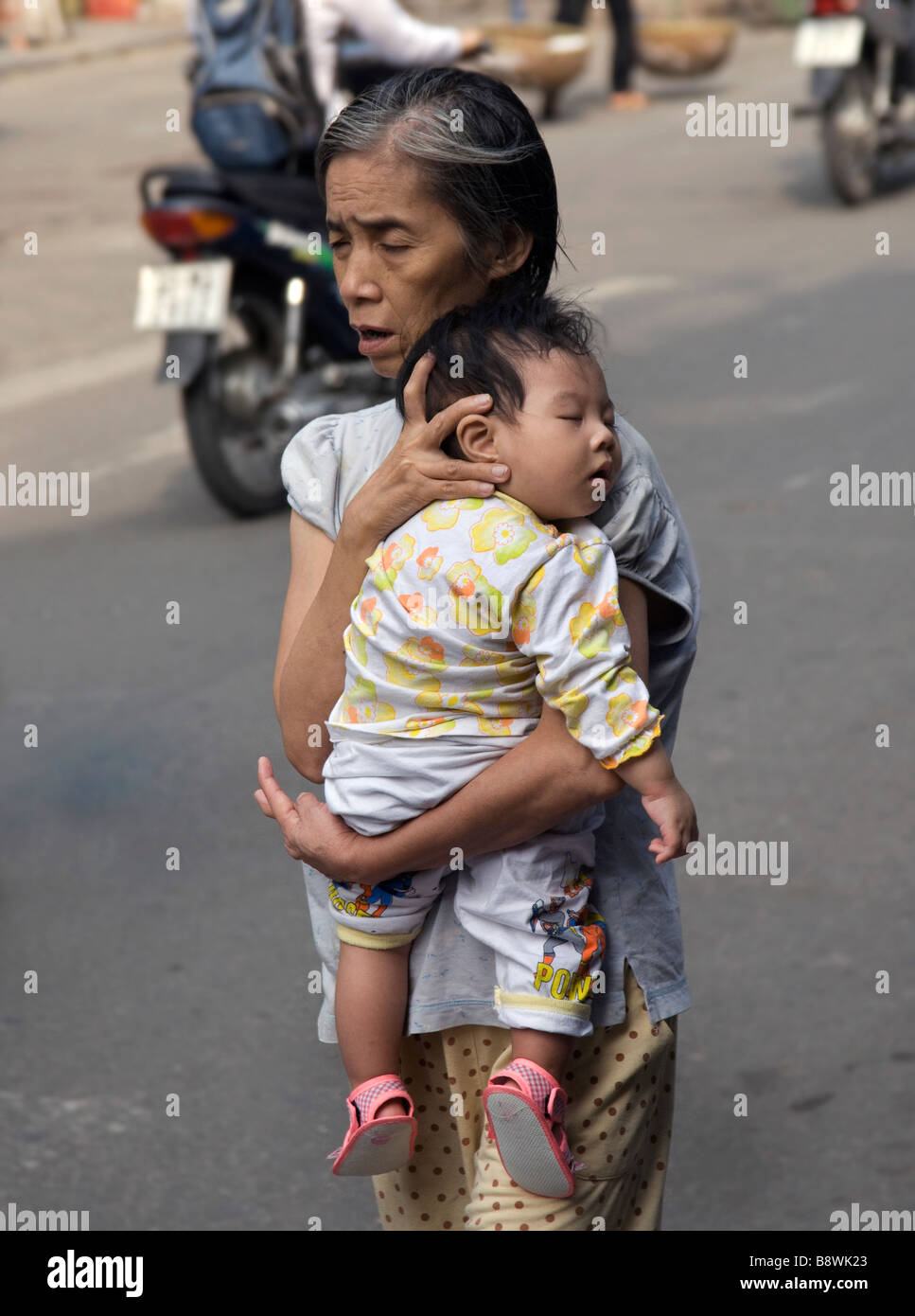 Vietnamienne avec la mendicité des enfants au bord de la route, Saigon, Vietnam Banque D'Images