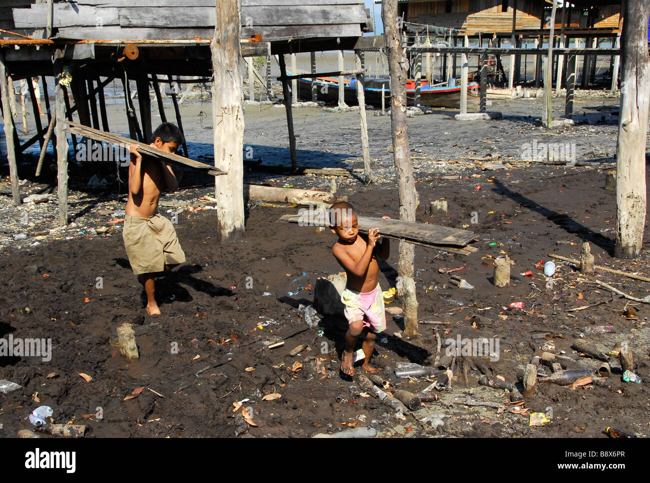 Sea Gypsy Moken petit garçon travaillent, transportant du bois pour construire leur nouvelle maison. Lhao Island,Ranong,le sud de la Thaïlande. Banque D'Images