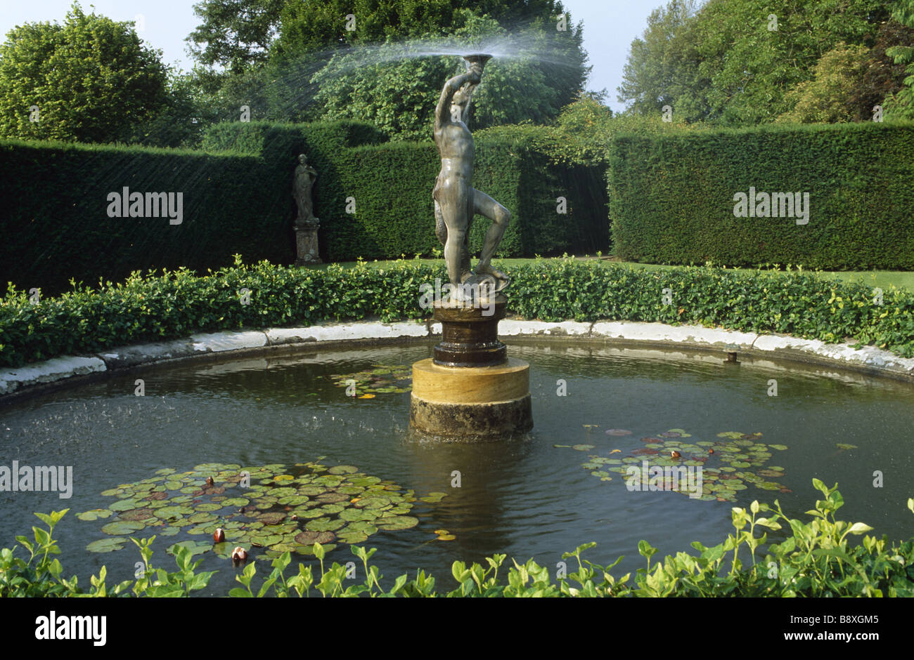 L'étang de jardin Lytes Cary Manor avec statue/fontaine et nénuphars. L'arbousier est un point central dans ce domaine. Banque D'Images