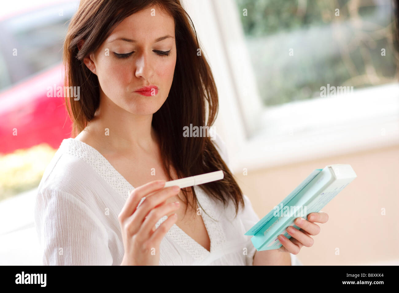 Femme à la recherche de résultats de test de grossesse Banque D'Images