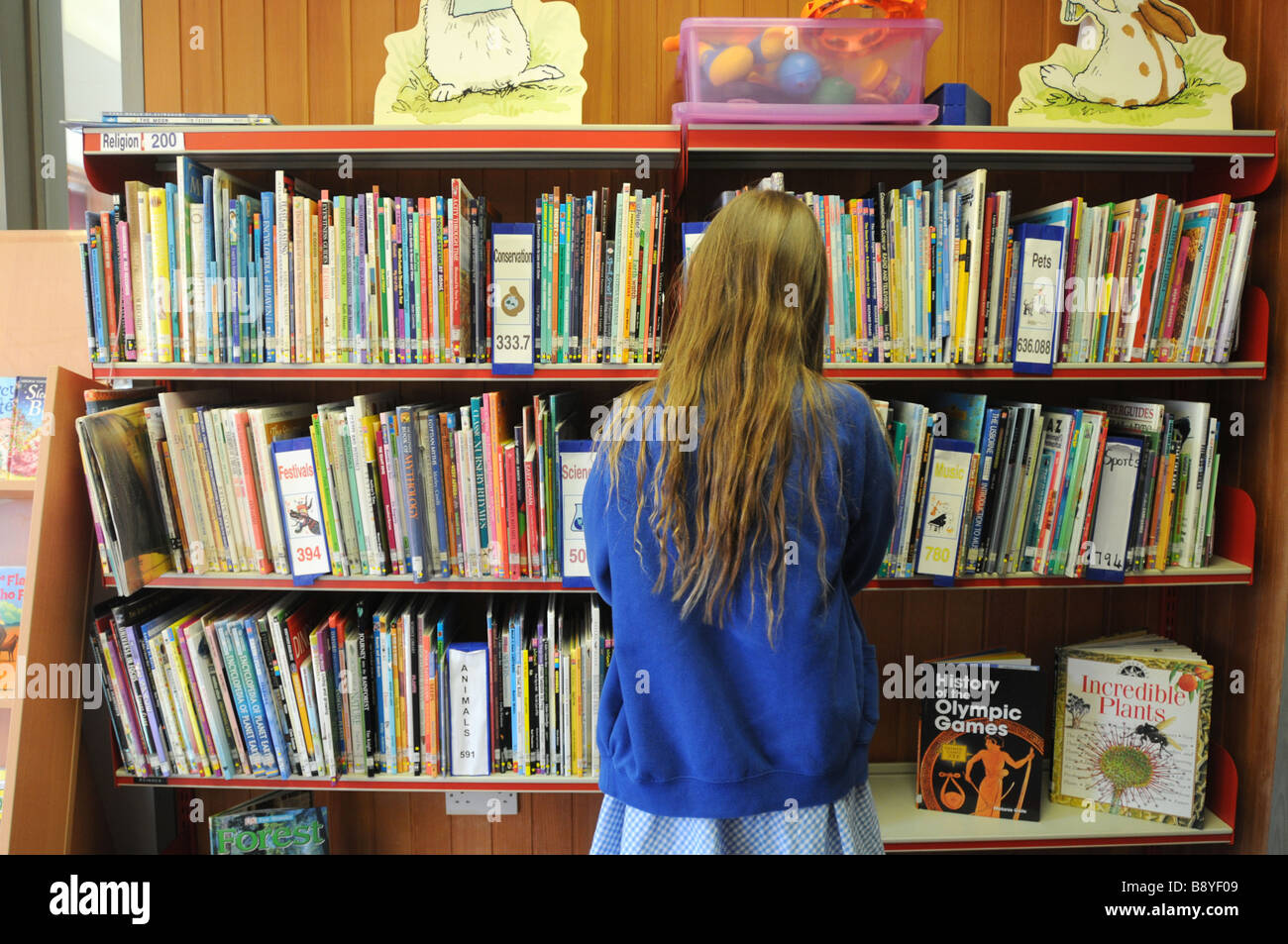 Une jeune fille de 11 ans la lecture dans sa bibliothèque Banque D'Images