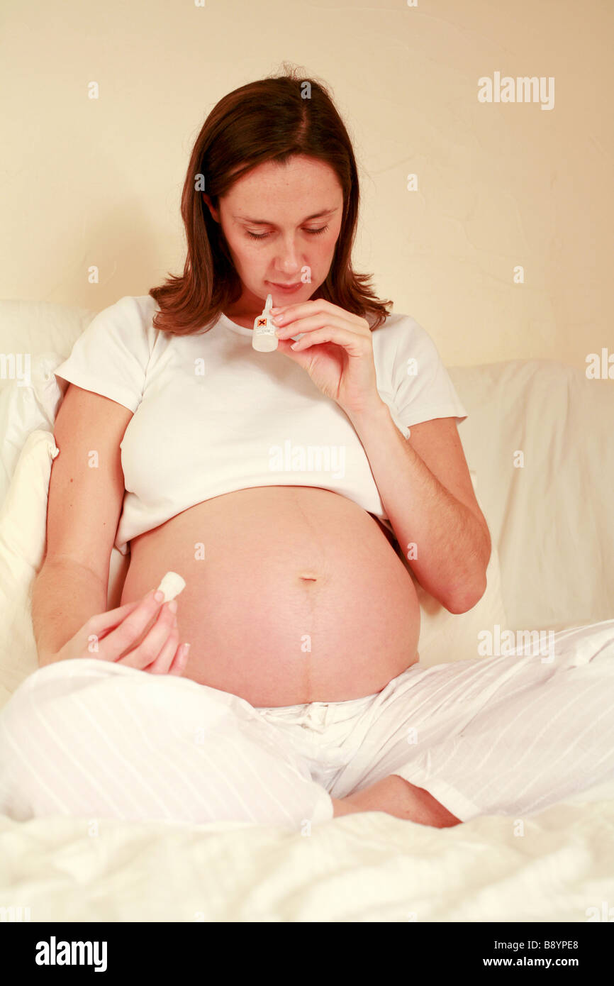 Jeune femme enceinte avec des foetus foetus estomac bosse se détend à la maison et renifle colle toxique pour obtenir une haute chimique Banque D'Images