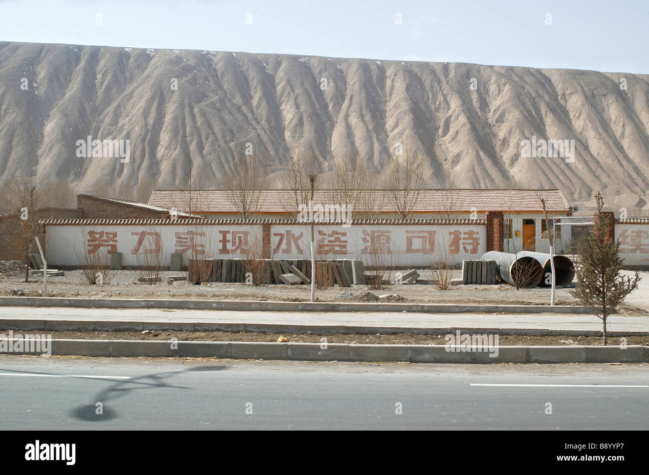 Construction routière avec grande calligraphie chinoise sur le mur il y a une montagne derrière Banque D'Images