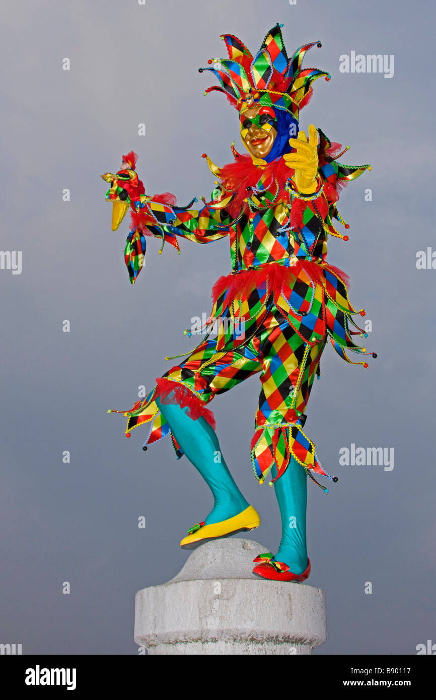 Carnaval de Venise.perché pleine longueur couleurs Arlequin Costume chapeau et masque. Venise Vénétie Italie Europe 92547 verticale-Venise Banque D'Images