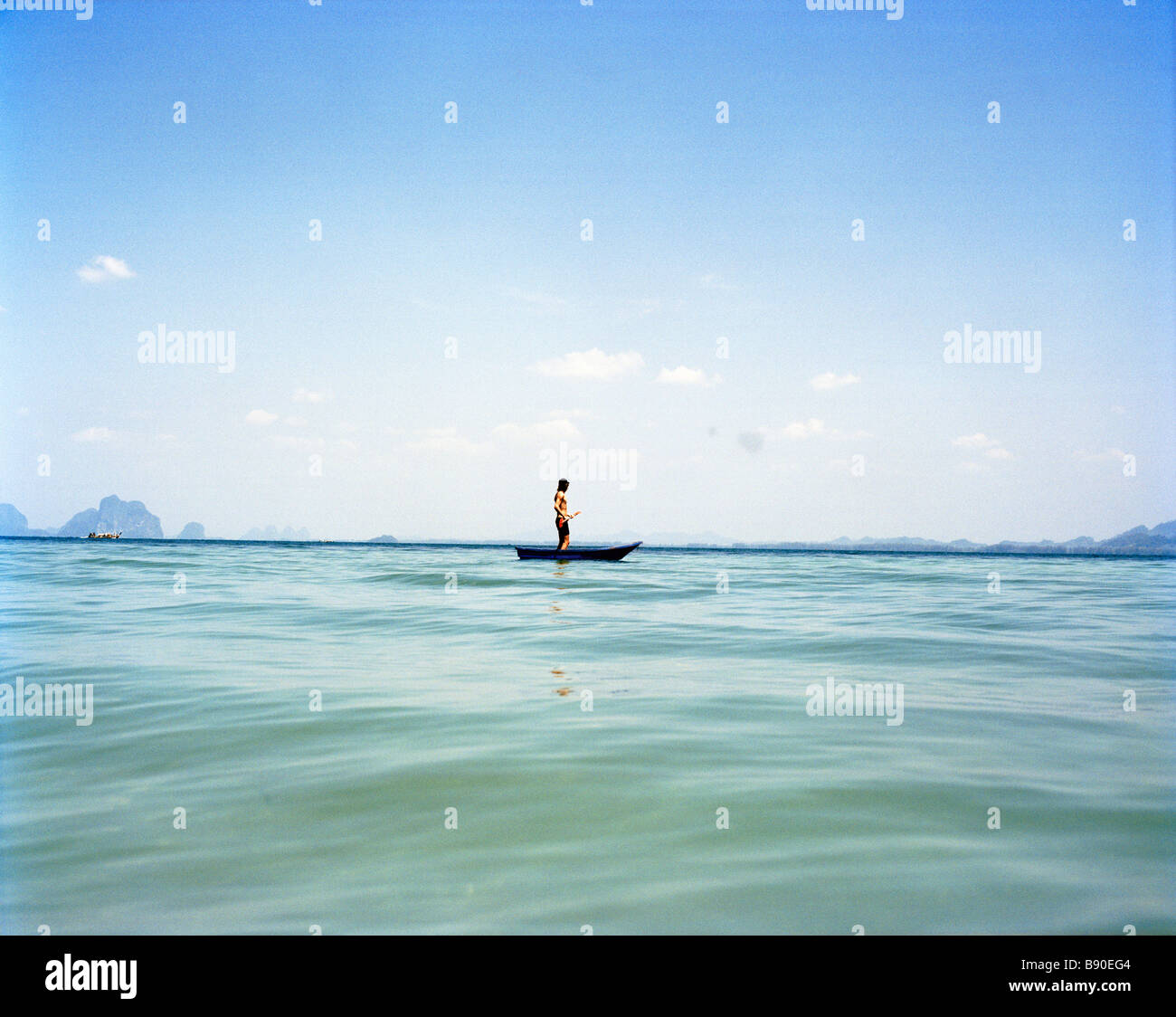 Un homme dans un petit bateau sur la mer bleue de la Thaïlande. Banque D'Images